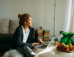 Woman in living room with laptop, embodying balanced wellness and daily vitality.